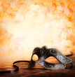 Masquerade. Venetian carnival mask with glittering orange background and copy space.