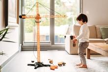 Little Toddler Boy Playing With Big Construction Building Crane Toy At Home In Living Room. Child Leisure Activity, Creative Game, Using Imagination.