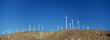 Group of aligned windmills against blue sky