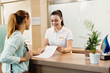 Happy receptionist talking to a customer at health spa.