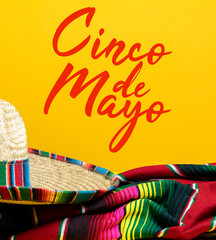Mexican Serape blanket and sombrero on yellow background with Cinco de Mayo. 