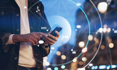 Closeup image of male hands with smartphone at night on city street, searching internet or social networks, hipster man typing an sms message on chat
