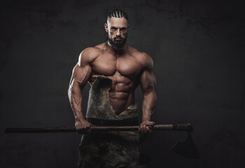 Wall Mural - Brutal bodybuilder in fashion of ancient furios viking posing with naked torso and dreadlock in dark dirty background.