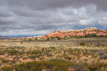 Rounded Red Cliffs Against A Cloudy Sky And Plateaus Covered With Dry Vegetation.