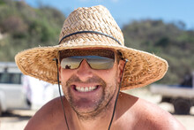 man grinning in straw hat at the beach
