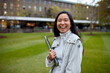 © Jonah Ritchie/Austockphoto - Young Asian student holding her laptop on lawn at university campus