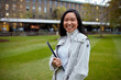 © Jonah Ritchie/Austockphoto - Young Asian student holding her laptop on lawn at university campus