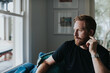 © Jonah Ritchie/Austockphoto - Thoughtful man looking through window while sitting on sofa at home