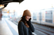 © Jonah Ritchie/Austockphoto - Young woman waiting at train station talking on mobile phone