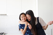 © Jonah Ritchie/Austockphoto - Portrait of smiling mother embracing her daughter in kitchen