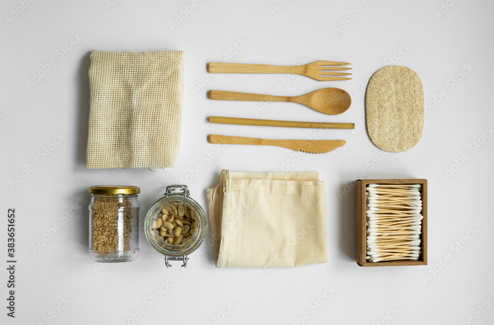 Zero waste kit. Set of eco friendly bamboo cutlery, mesh cotton bags, glass jars with a nuts, loofah sponge and box of cotton swabs. Natural and reusable items accessories on gray surface. - obrazy, fototapety, plakaty 
