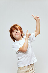 Wall Mural - Cheerful red-haired boy smile index fingers on top gestures with hands Copy Space