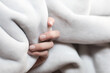 Close up macro of a female woman hand holding a soft luxurious grey warm winter blanket lit by natural light background cozy touch hold fingers winter warm coz