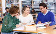 © JackF - Young female students sitting in university library, working with professor..