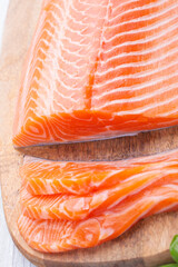 Raw fresh salmon fillet cut into slices and piece on wooden board