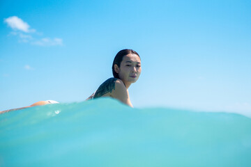 Portrait of surfer girl on surf board in blue ocean