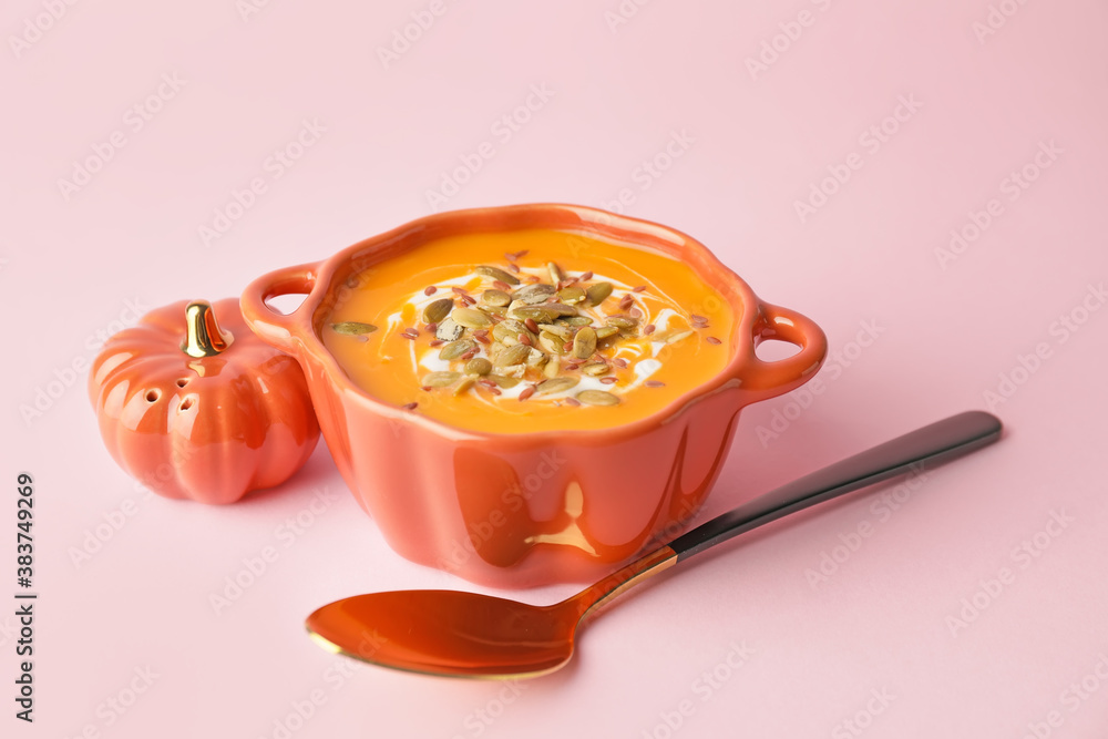 Tasty pumpkin cream soup in pot on color background
