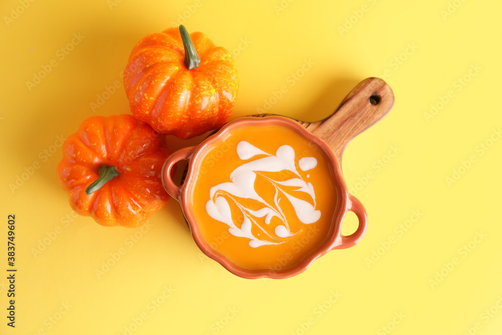 Tasty pumpkin cream soup in pot on color background