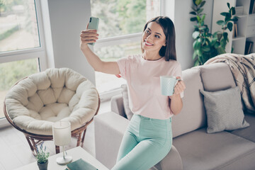 Sticker - Photo portrait of female social media influencer showing her morning routine holding cup making selfie indoors