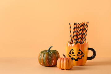 Wall Mural - Halloween fun party decorations, pumpkins, mug with drinking straw on orange background. Horizontal composition with copy space.