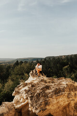 Wall Mural - A couple in love  sits on the big stone with a breathtaking mountains view on the background.  Copy space.