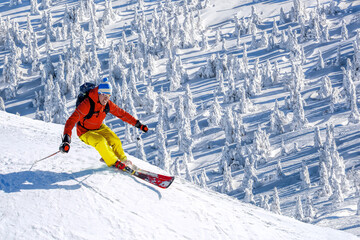 Wall Mural - Skier skiing downhill in high mountains against blue sky