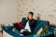 © eduard - Stressful man  holding hands on the temples with close eyes, while sitting on the sofa at home. Stressed man suffer from headache bad. Peaceful break in home office.