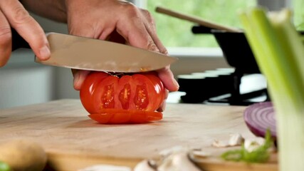 Canvas Print - man cutting fresh red tomato in kitchen