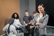 © Johnér - Woman looking at camera, coworkers at meeting on background