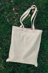 Wall Mural - White blank cotton bag on green grass. Mockup and zero waste concept.