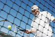 Happy senior man in sports clothing playing tennis
