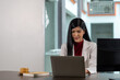 © suwanb - Portrait of young business woman using laptop computer on desk in office.