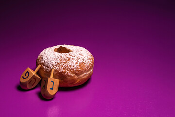 Wall Mural - Sufganiya and wooden dreidels for Jewish holiday Hanukkah on violet background.