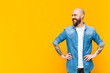 young bald and bearded man looking happy, cheerful and confident, smiling proudly and looking to side with both hands on hips