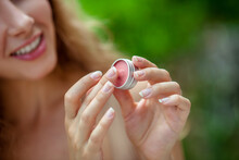 Pretty Young Woman Holding Lip Balm In Her Hand And Smiling
