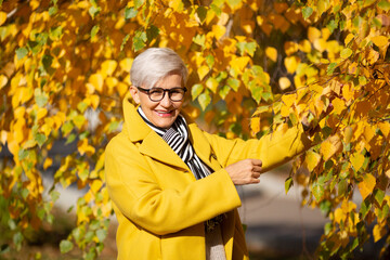 adult woman in yellow coat in the park in autumn