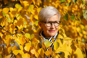 adult woman in yellow coat in the park in autumn