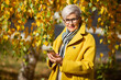 adult woman in glasses in the park in autumn with a mobile phone