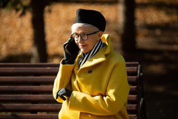 adult woman in glasses in the park in autumn with a mobile phone