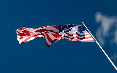 US national flag waving in the wind against a blue sky background low angle close up. Stars and Stripes American Old Glory. 