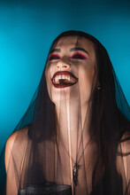 Evil Bride With Dark Makeup And Veil Laughing On Blue