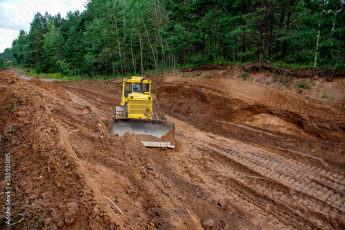 Dozer during clearing forest for construction new road . Yellow Bulldozer at forestry work Earth-moving equipment at road work, land clearing, grading, pool excavation, utility trenching