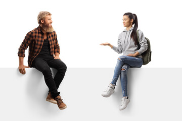 Bearded guy laughing and talking to a female student seated on a blank panel