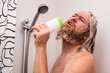 © Володимир Захаров - Handsome bearded man singing while taking shower at home using shampoo bottle instead of microphone. Happy caucasian guy sings with facial expression enjoying life.