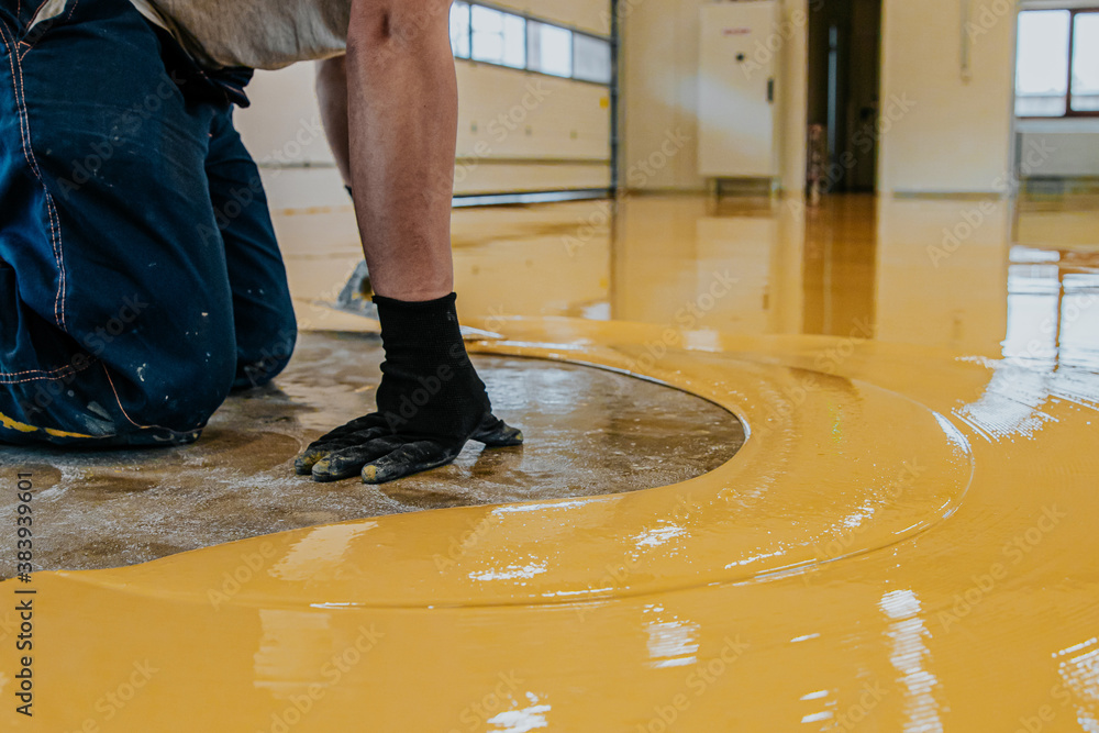 Worker, coating floor with self-leveling epoxy resin in industrial workshop. - obrazy, fototapety, plakaty 
