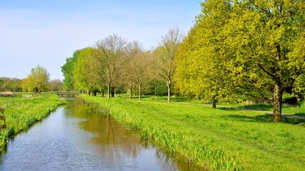 Classic Dutch landscape. Polder ditch canal on a green grass field.