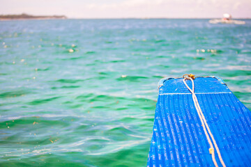 Poster - Small blue boat in open sea on desert island