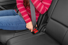 A Woman Fastening Seat Belt In Back Seat Of Car.