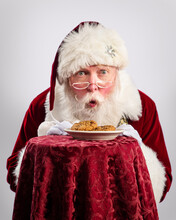 Santa Claus Picking Up Christmas Cookies On The Plate, Isolated On White Background
