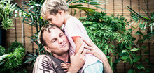Father Gently Hugs Son, Eyes Closed With Pleasure, Blond Little Child Boy Kiss Daddy Head Top, Face To Face, Bright Sun Light Green Leaves Back. Happy Childhood, Fatherhood Love Feelings, Fathers Day